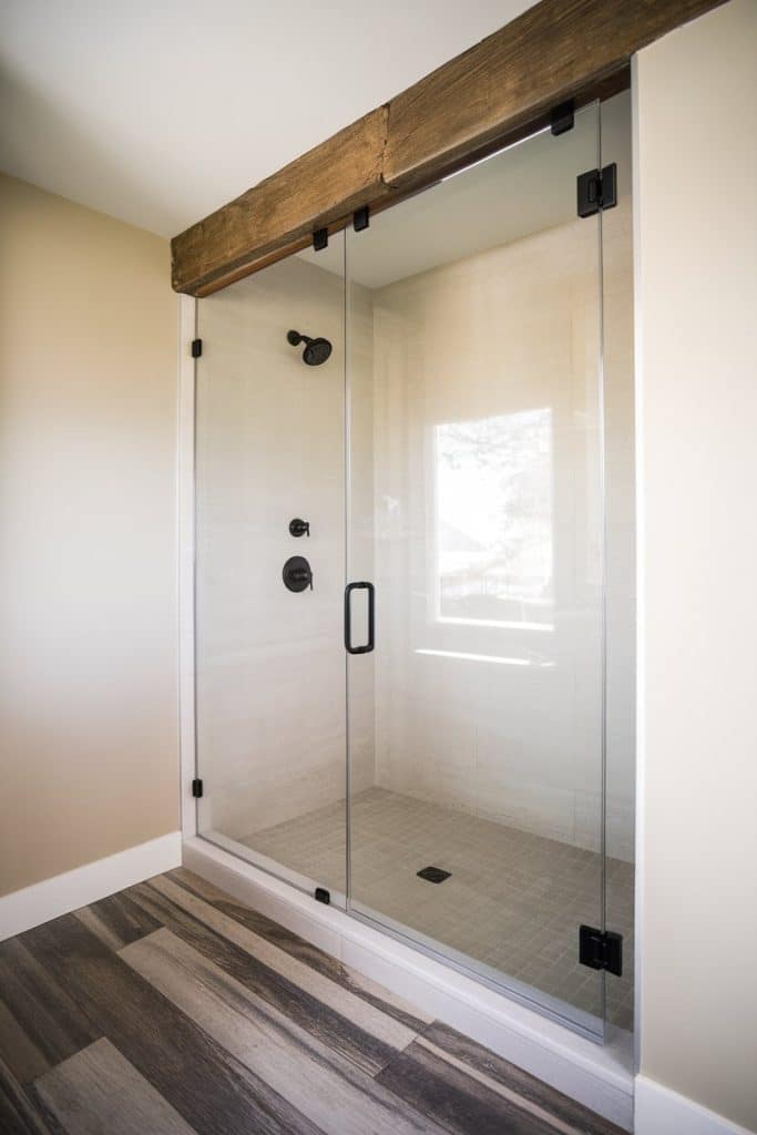Walk-in shower with a swinging door in a small bathroom.