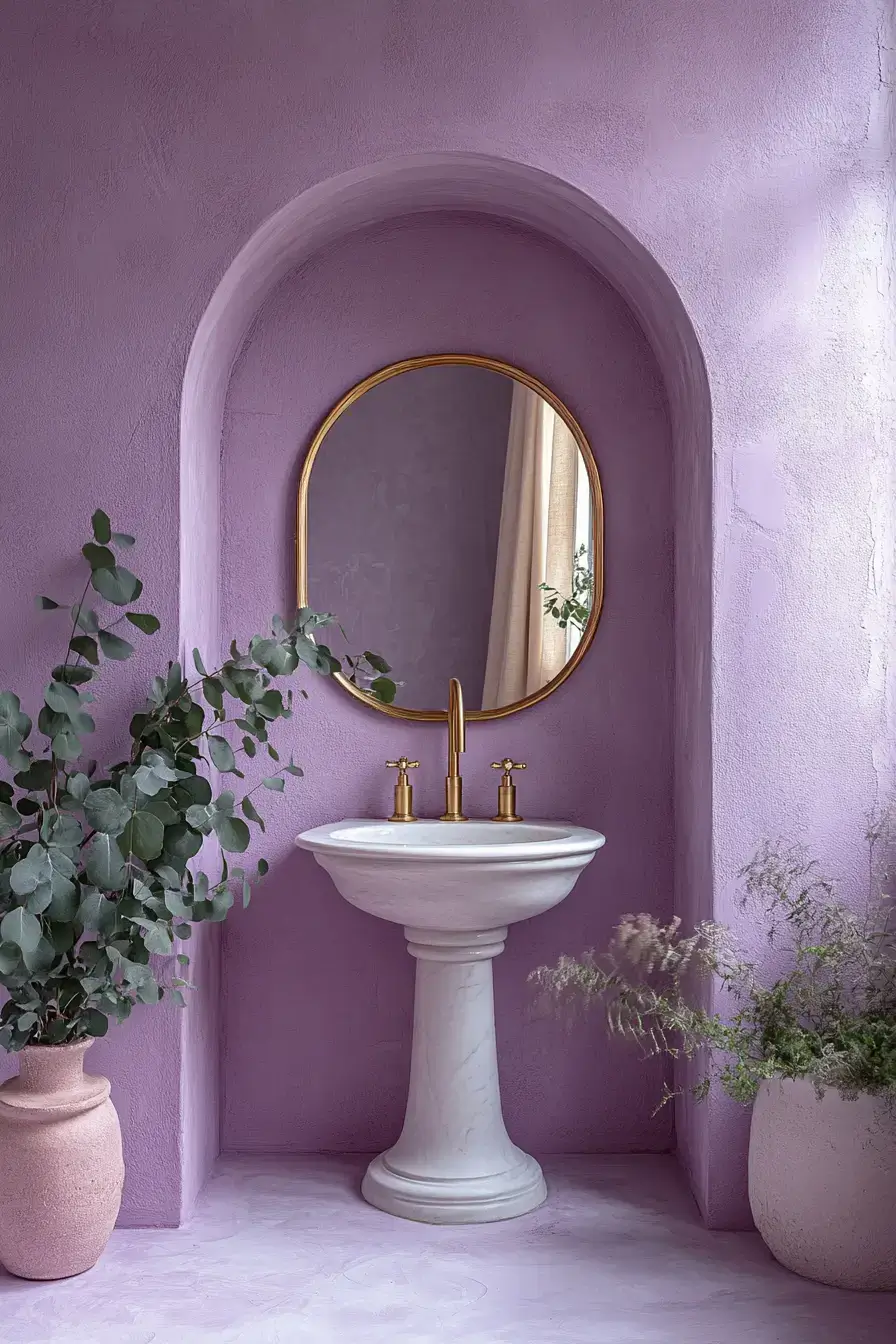 A lilac bathroom with brass fixtures, marble, and fresh greenery